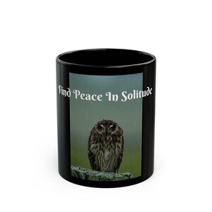 May include: Black ceramic mug featuring an image of an owl perched on a rock, with the text "Find Peace In Solitude" in white. The owl has brown and white feathers, set against a green and gray background.