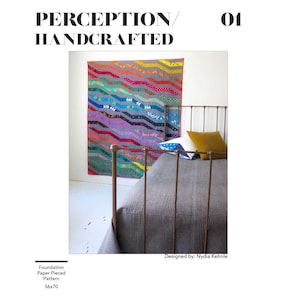 May include: A colourful quilt with a wavy pattern hangs on a white wall above a bed with a grey duvet and a gold metal frame. The quilt is made of various fabrics in shades of red, orange, yellow, green, blue, purple, and grey. The quilt is titled "Perception/Handcrafted 01" and is designed by Nydia Kehnle. The quilt is described as a foundation paper pieced pattern, 56x70.