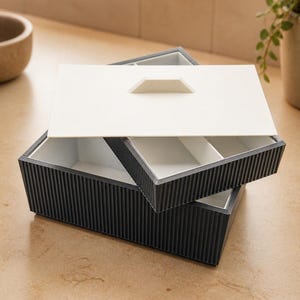 May include: A rectangular storage box with a dark gray ribbed exterior and a white interior. The box features a removable white lid with a central handle and an internal white divider tray that sits inside the main compartment for organization.