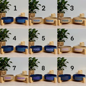 May include: A collection of ceramic pet bowls in various colors, including blue and tan. Each bowl is labeled with "FOOD" or "WATER" in a contrasting color. The bowls are set on wooden stands, with plants and candles in the background.