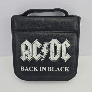 May include: Black CD case featuring the AC/DC logo with a lightning bolt and the text "BACK IN BLACK" in white. The case has a handle and a textured surface.