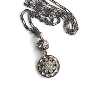 Art deco styled necklace with antique brass figaro chain with a Swarovski clear crystal ball attached to a 15mm brilliant Swarovski clear crystal three tiered disc with one large Swarovski crystal in the center. Choose from 16, 18 or 20 inch chain.