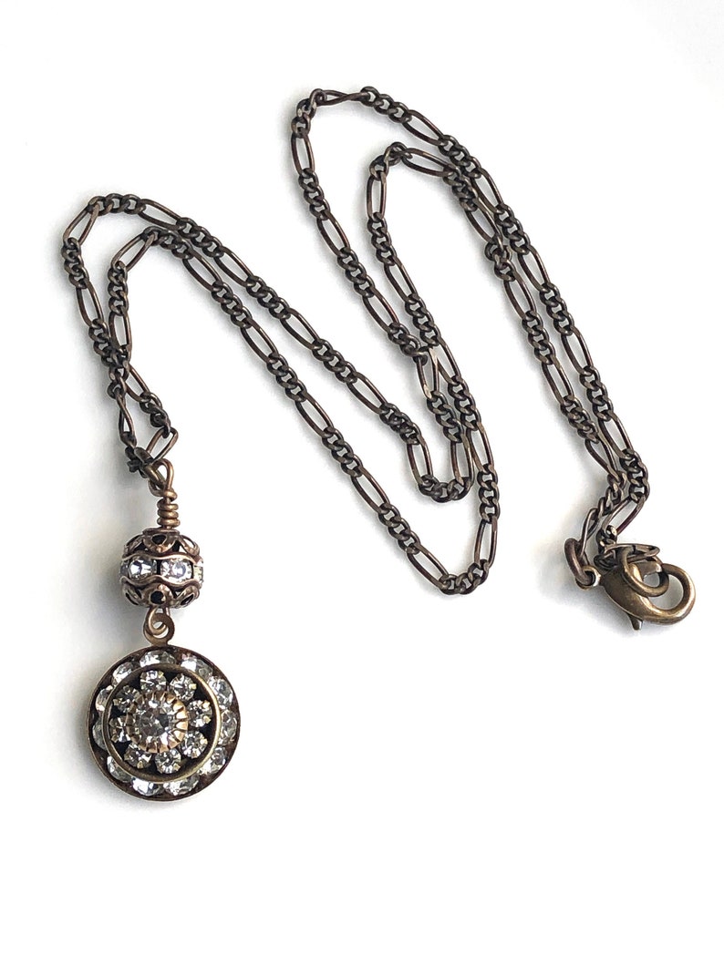 Brass art deco crystal pendant with Swarovski crystal round pendant with three tiers of Swarovski crystals suspended from a brass Swarovski crystal ball. Antique brass chain in 16, 18 or 20 inches. Lobster clasp with Nickel and lead free chain.