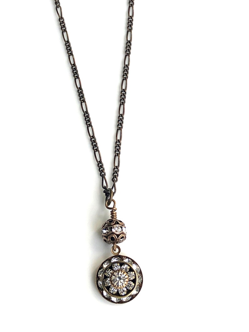 Brass art deco crystal pendant with Swarovski crystal round pendant with three tiers of Swarovski crystals suspended from a brass Swarovski crystal ball. Antique brass chain in 16, 18 or 20 inches. Lobster clasp with Nickel and lead free chain.