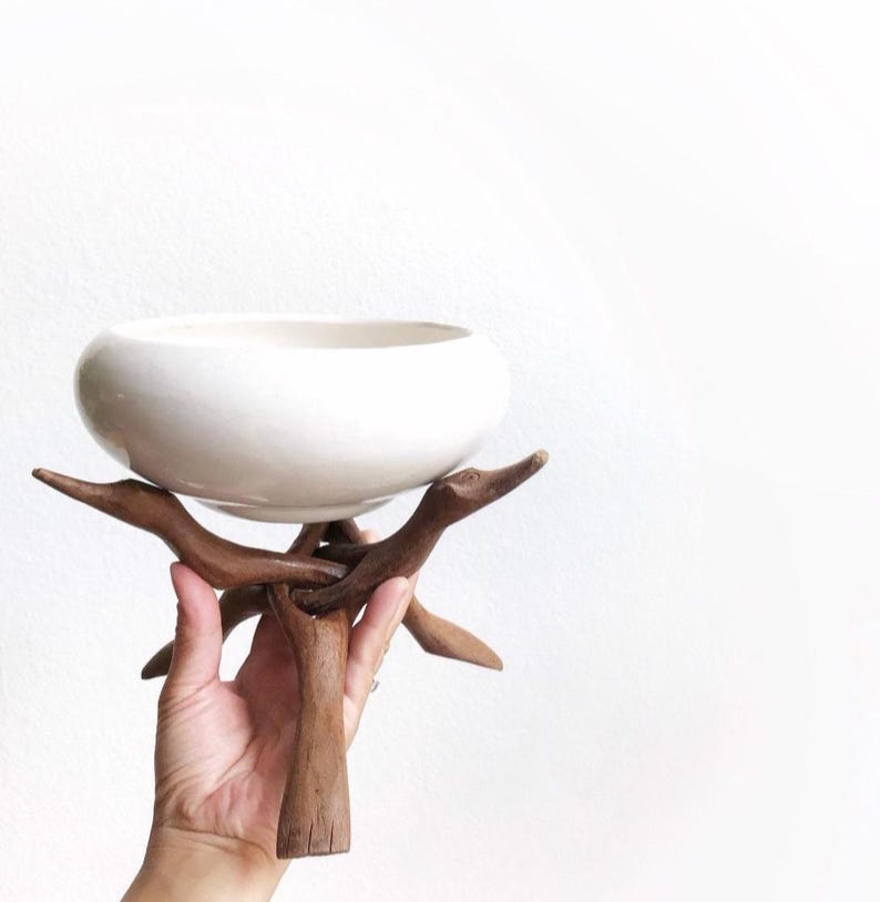 Może przedstawiać: Biała ceramiczna miska na drewnianym stojaku wykonanym z gałęzi. Stojak ma unikalny, naturalny design z trzema nogami.