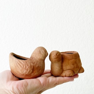 Puede incluir: Un juego de tres tazas de cerámica con un acabado moteado y mate. Las tazas son de color crema, gris claro y gris oscuro. Cada taza tiene un diseño simple y minimalista.