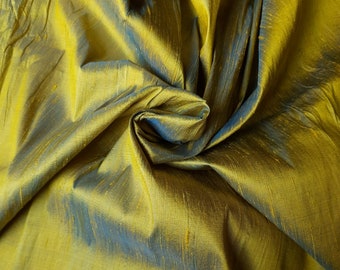 May include: A close-up of a golden fabric with a subtle blue sheen. The fabric is draped and folded, creating a soft, luxurious texture.