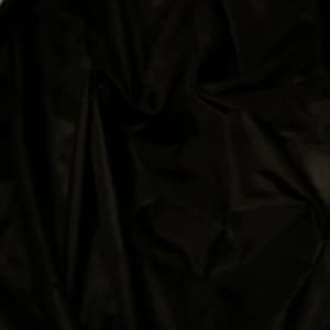 May include: Black fabric with a smooth, silky texture. The fabric is draped and folded, creating soft folds and wrinkles.