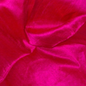 Könnte beinhalten: Nahaufnahme eines leuchtend pinkfarbenen Stoffes mit einer glatten, seidenartigen Textur. Der Stoff ist drapiert und gefaltet und erzeugt weiche, fließende Linien.