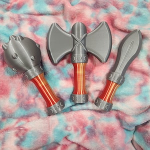 May include: Three toy weapons: a mace, an axe, and a sword. The mace has a gray head with rounded studs and a red and gray handle. The axe has a gray head and a red and gray handle. The sword has a gray blade and a red and gray handle.
