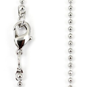 May include: A silver ball chain necklace with a lobster clasp closure.