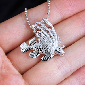 Op de afbeelding: Zilveren lionfish-hangerketting met een delicaat, gedetailleerd ontwerp. De hanger is bevestigd aan een zilveren bolketting.