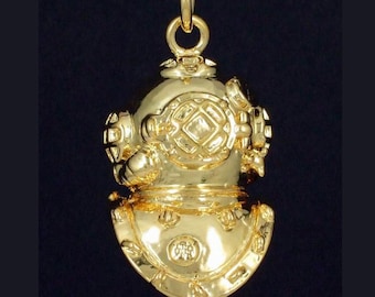 May include: A gold-colored diving helmet pendant necklace. The pendant is detailed with a textured surface and a small round window. The necklace is on a black cord.