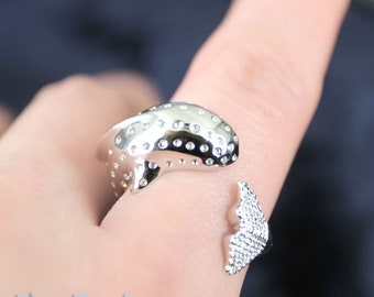 May include: A silver ring featuring a whale design with a dotted texture. The whale's tail is separate from the body and is also dotted.