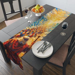 May include: A dining table set with a decorative table runner featuring an abstract painting in shades of yellow, blue, and red. The table is set with plates, silverware, wine glasses, and a bowl of apples. The table and chairs are dark wood.