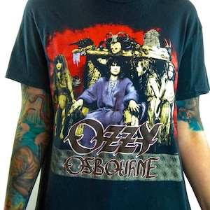 May include: Black t-shirt with a graphic print of Ozzy Osbourne in a throne surrounded by figures. The text "Ozzy Osbourne" is printed in a stylized font below the image.