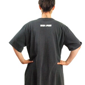 May include: A black oversized t-shirt with the text "BIG PUN" printed on the back. The person is wearing red leggings.