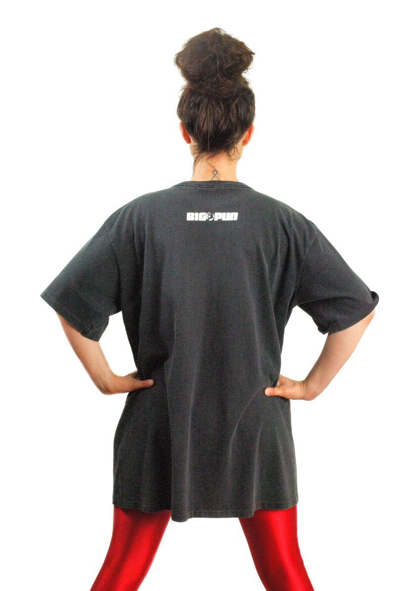 May include: A black oversized t-shirt with the text "BIG PUN" printed on the back. The person is wearing red leggings.