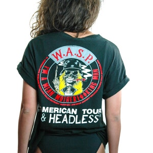 May include: Black t-shirt with a white graphic of a skull wearing a hat and smoking a cigar. The graphic includes the text "W.A.S.P. I'm a Mean Motherf**king Man" and "American Tour & Headless".