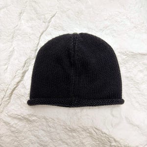 Puede incluir: Un gorro negro liso con un borde doblado. El gorro est&aacute; hecho de un material de punto y se muestra sobre una superficie blanca texturizada. Este gorro sencillo y cl&aacute;sico es adecuado para el clima fr&iacute;o.