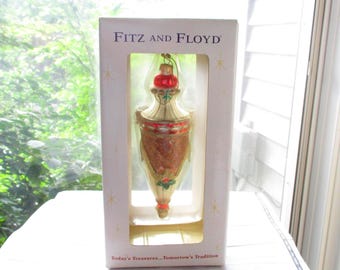 May include: A Fitz and Floyd Christmas ornament in a box. The ornament is gold, red, and brown, with a decorative design. The box has the brand name and the text "Today's Treasures...Tomorrow's Tradition".
