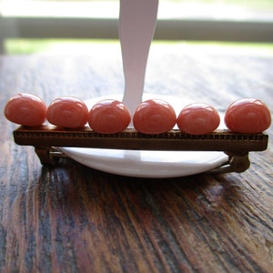 May include: A gold-toned bar brooch with six pink oval-shaped stones.