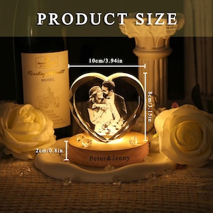May include: A heart-shaped crystal block featuring an engraved photograph of a couple, mounted on a round wooden base with the text "Peter & Jenny" printed on the front. The crystal measures 3.94 inches wide by 3.15 inches high, with a 0.8 inch base.