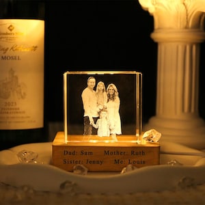 May include: A clear rectangular glass block featuring a laser-etched family portrait, illuminated from below by a wooden base. The base is engraved with the text: Dad: Sam, Mother: Ruth, Sister: Jenny, Me: Louis, creating a personalized display piece.