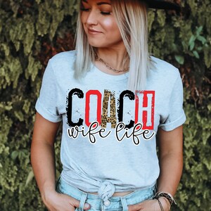Peut inclure: Un t-shirt gris clair avec le texte "COACH wife life" en noir, rouge et imprim&eacute; l&eacute;opard.