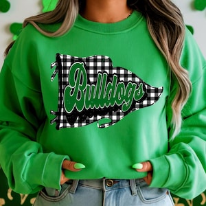 May include: A vibrant green sweatshirt displaying a black and white checked flag design with the word "Bulldogs" in green script. The sweatshirt has long sleeves and a crew neck.