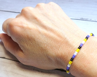 May include: A beaded bracelet with alternating black, white, yellow, and purple beads.