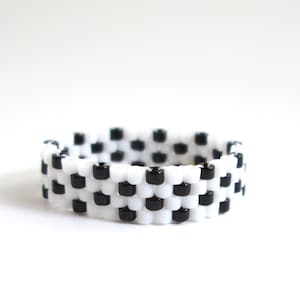 Puede incluir: Un anillo de cuentas con un patrón de tablero de ajedrez en blanco y negro.