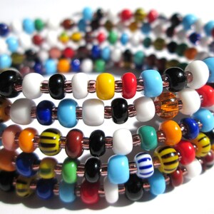 May include: Multicoloured glass beads strung on a wire, creating a layered bracelet. The beads are in various colours, including white, blue, red, yellow, orange, green, and black.