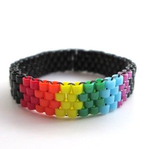 May include: A rainbow beaded ring with a black base. The beads are arranged in the order of the rainbow, with red, orange, yellow, green, blue, and purple beads.