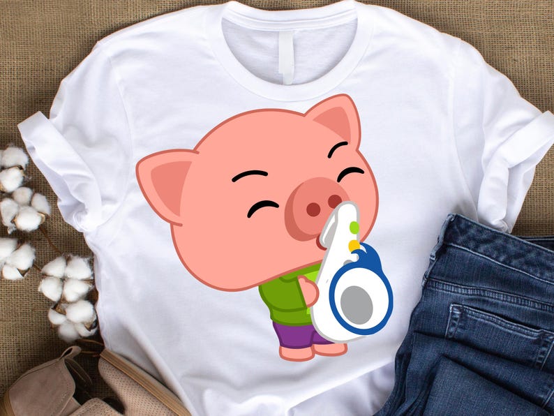 May include: White t-shirt featuring a cartoon pig playing a saxophone. The pig is pink with a green shirt and purple pants. The saxophone is white and blue. The shirt is paired with blue jeans.