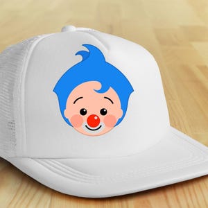 May include: White trucker hat featuring a cartoon clown face with blue hair, a red nose, and a smiling expression. The hat has a mesh back and a curved brim, suitable for sun protection.