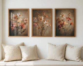 以下が含まれることがあります： 3つの額入り花の絵画。各プリントは、白、桃色、赤の色合いの花束を、落ち着いた背景に描いています。フレームは温かみのある茶色です。ニュートラルカラーのクッションが置かれたベンチの上に飾られています。