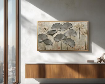 May include: A rectangular wall art piece in a thin gold frame featuring a botanical illustration of grey lotus leaves and pale cream lotus flowers on a textured, light-colored background with subtle hints of warm orange and brown tones.