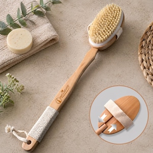 May include: A wooden back brush with natural bristles and a long handle. The brush head is oval-shaped and attached to a light-colored wooden handle. The handle has a rope grip and a loop for hanging. The brand name "INCLISSHOP" is printed on the handle.