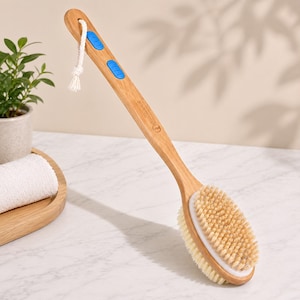 May include: A wooden back brush with a long handle and oval brush head. The handle has two blue grip pads and a white rope loop. The brush head features natural bristles and a white border. The brush is designed for body care.