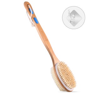 Puede incluir: Un cepillo de espalda de madera con un mango largo y dos cabezales. Un lado presenta cerdas naturales, el otro un material más suave y de color más claro. El mango tiene detalles en azul y un lazo de cuerda para colgar. También se incluye un gancho adhesivo transparente.