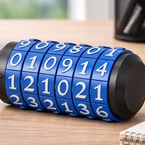 Puede incluir: Un candado de combinación azul con números blancos se muestra sobre una superficie de madera. El candado tiene forma cilíndrica con diales giratorios. Otros elementos incluyen llaves, un bolígrafo y un bloc de notas.