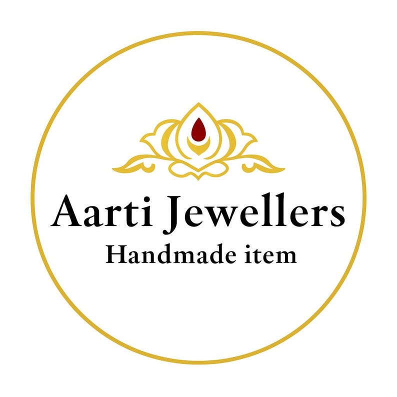 May include: Aarti Jewellers logo in a gold circle on a white background. The logo features a gold floral design with a red center and the text "Aarti Jewellers Handmade item" in black.