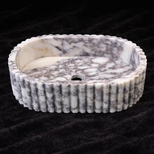 Puede incluir: Una taza de cer&aacute;mica blanca con un asa negra y el texto "But First, Coffee" en negrita negra. La taza est&aacute; sobre una superficie de madera. La taza mide 10 cm de alto.