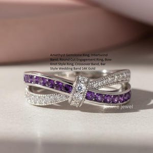 May include: A silver-colored ring with a bow-knot design. The ring features a row of small, round, purple gemstones and a row of small, clear gemstones. The ring has the text "Amethyst Gemstone Ring, Intertwind Band, Round Cut Engagement Ring, Bow Knot Style Ring, Crossover Band, Bar Style Wedding Band 14K Gold".