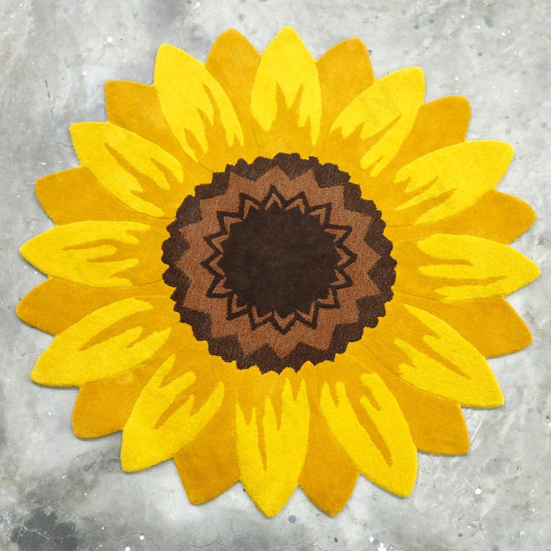 IN-108 Hand Tufted Sunflower Woolen Carpet for Floor Decor, Cozy Home,Bedroom, Courtyard, Living Room, Kids, Cabin, Bedroom, Reading Nook.
A vibrant sunflower-shaped wool rug handcrafted in rich yellow and brown tones, featuring realistic petal textures and a plush wool surface. Displayed in a bright minimalist room with indoor plants, natural sunlight, and a wooden bench, this handmade rug adds a cheerful botanical touch and cozy warmth to any modern living space.