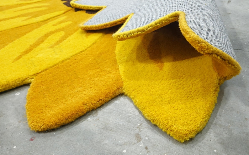 IN-108 Hand Tufted Sunflower Woolen Carpet for Floor Decor, Cozy Home,Bedroom, Courtyard, Living Room, Kids, Cabin, Bedroom, Reading Nook.
A vibrant sunflower-shaped wool rug handcrafted in rich yellow and brown tones, featuring realistic petal textures and a plush wool surface. Displayed in a bright minimalist room with indoor plants, natural sunlight, and a wooden bench, this handmade rug adds a cheerful botanical touch and cozy warmth to any modern living space.