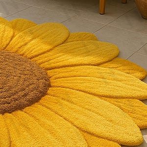 IN-108 Hand Tufted Sunflower Woolen Carpet for Floor Decor, Cozy Home,Bedroom, Courtyard, Living Room, Kids, Cabin, Bedroom, Reading Nook.
A vibrant sunflower-shaped wool rug handcrafted in rich yellow and brown tones, featuring realistic petal textures and a plush wool surface. Displayed in a bright minimalist room with indoor plants, natural sunlight, and a wooden bench, this handmade rug adds a cheerful botanical touch and cozy warmth to any modern living space.