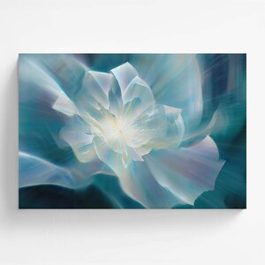 Puede incluir: Una impresión de arte mural rectangular que presenta una flor abstracta y etérea en tonos azul claro, blanco y azul verdoso profundo. Los pétalos parecen irradiar desde un centro brillante con un efecto de movimiento suave.