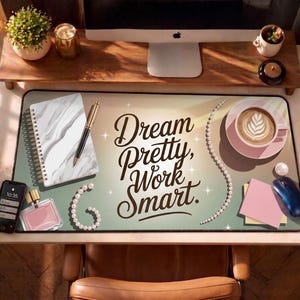 May include: A desk setup featuring a mousepad with the text "Dream Pretty, Work Smart." The scene includes a marble notebook, a gold pen, a cup of coffee, a smartphone, and a perfume bottle. A computer monitor and desk accessories are in the background.